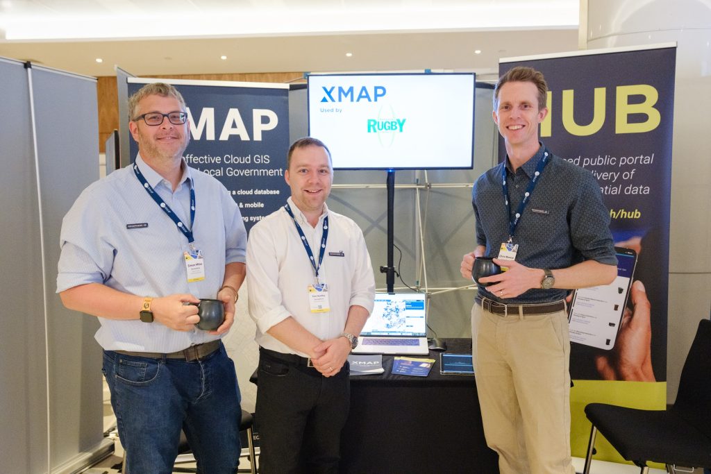 Simon, Tom and Chris stood in front of a stand at the GeoPlace event