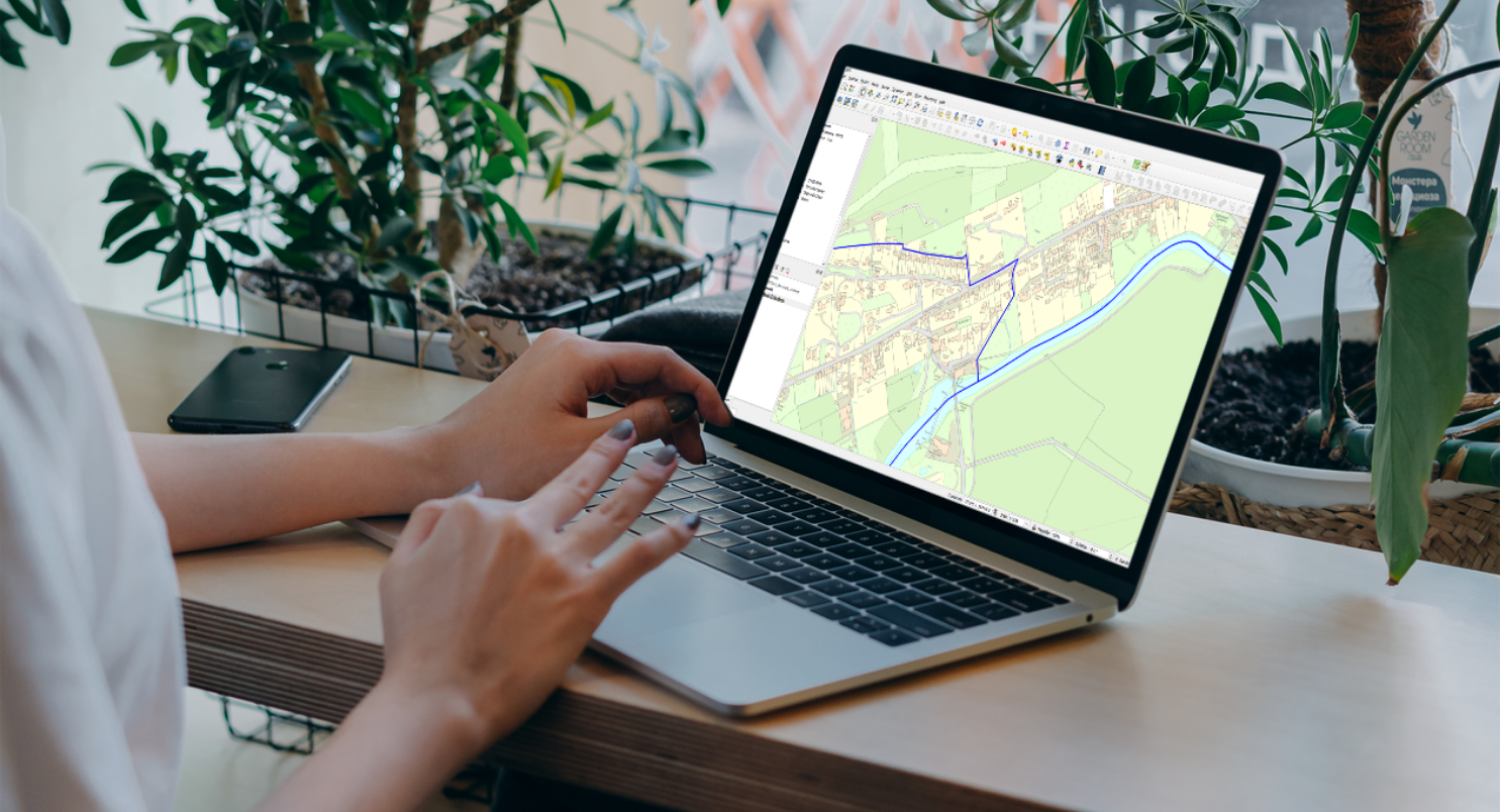 Laptop running QGIS displaying WMS feeds of OS mapping. It looks like the lady has 3 fingers.